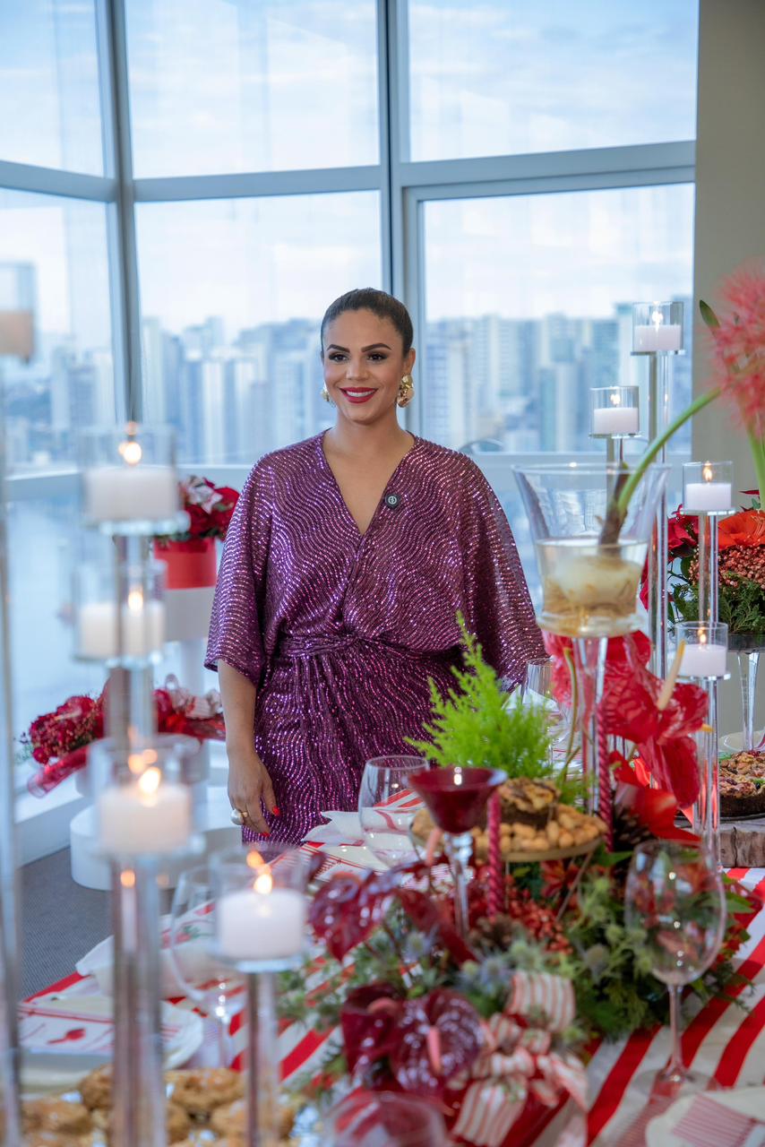 Cláudia, da Picnic Vitória, em um evento com decoração de flores e velas